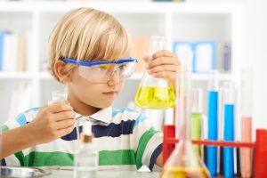 Boy in goggles holding flask with chemical reagent